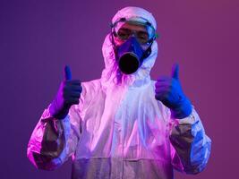 Coronavirus covid-19 pandemic. Doctor scientist wearing protective biological suit and mask due to global healthcare epidemic warning and danger background in blue and pink neon lights background. photo
