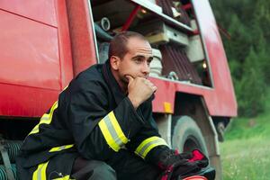 depressed and tired firefighter near fire truck. photo