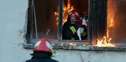 Firefighter hero carrying baby girl out from burning building area from fire incident. Rescue people from dangerous place photo