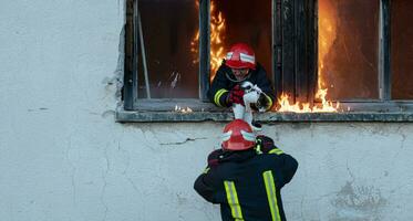 bombero héroe que lleva bebé niña fuera desde ardiente edificio zona desde fuego incidente. rescate personas desde peligroso sitio foto