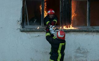 bombero héroe que lleva bebé niña fuera desde ardiente edificio zona desde fuego incidente. rescate personas desde peligroso sitio foto