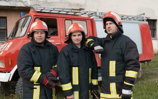 Group of fire fighters standing confident after a well done rescue operation. Firemen ready for emergency service. photo