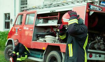 bombero con uniforme y casco estar en frente de eléctrico cable en un techo parte superior foto