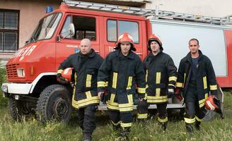 Group of fire fighters standing confident after a well done rescue operation. Firemen ready for emergency service. photo