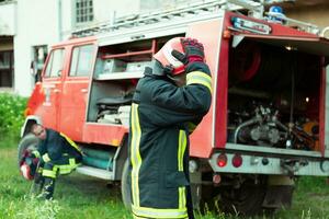 bombero con uniforme y casco estar en frente de eléctrico cable en un techo parte superior foto