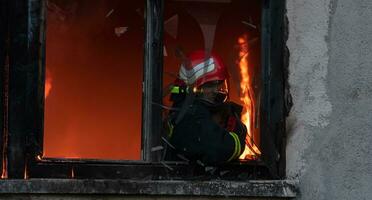 Firefighter hero carrying baby girl out from burning building area from fire incident. Rescue people from dangerous place photo