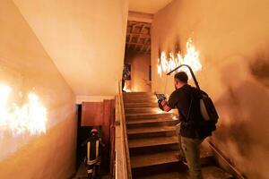 valiente bombero desciende escalera de un ardiente edificio y sostiene salvado niña en su brazos. abierto fuego. cineasta tomando disparar con Pro cine cámara y tres ejes cardán estabilización. bajo ligero foto