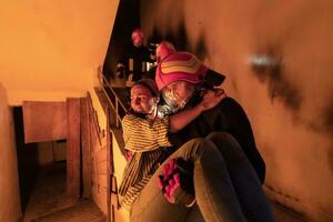 Brave Fireman Descends Stairs of a Burning Building and Holds Saved Girl in His Arms. Open fire and one Firefighter in the Background. photo