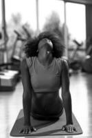 mujer afroamericana ejercicio yoga en el gimnasio foto