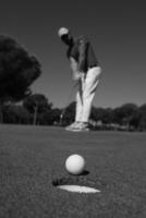 golf player hitting shot, ball on edge of hole photo