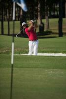 golfista golpeando un tiro de búnker de arena foto