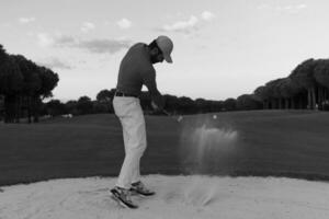 golfista golpeando un tiro de búnker de arena al atardecer foto