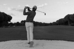 golfer hitting a sand bunker shot on sunset photo