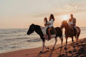 The family spends time with their children while riding horses together on a sandy beach. Selective focus photo