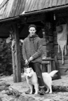 joven hipster con perro frente a una casa de madera foto