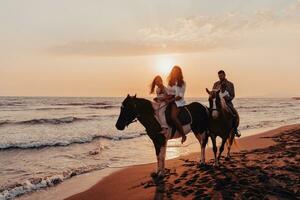 The family spends time with their children while riding horses together on a sandy beach. Selective focus photo