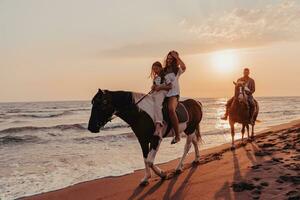 The family spends time with their children while riding horses together on a sandy beach. Selective focus photo