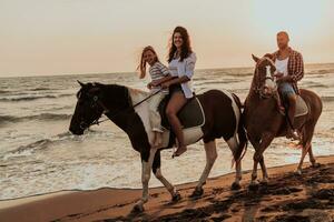 The family spends time with their children while riding horses together on a sandy beach. Selective focus photo