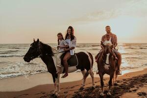 la familia pasa tiempo con sus hijos mientras montan a caballo juntos en una playa de arena. enfoque selectivo foto