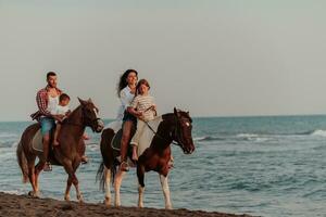 The family spends time with their children while riding horses together on a sandy beach. Selective focus photo