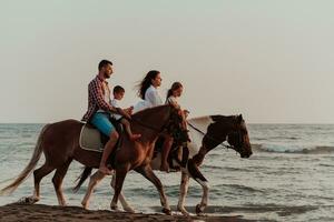 The family spends time with their children while riding horses together on a sandy beach. Selective focus photo