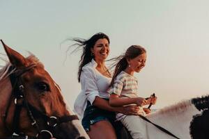 Mother and daughter enjoy riding horses together by the sea. Selective focus photo