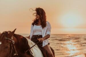 mujer vestida de verano disfruta montando a caballo en una hermosa playa de arena al atardecer. enfoque selectivo foto