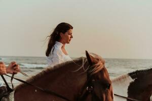 mujer vestida de verano disfruta montando a caballo en una hermosa playa de arena al atardecer. enfoque selectivo foto