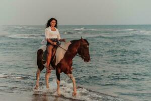 mujer vestida de verano disfruta montando a caballo en una hermosa playa de arena al atardecer. enfoque selectivo foto