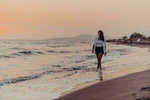 feliz mujer despreocupada disfrutando de la hermosa puesta de sol en la playa. enfoque selectivo foto