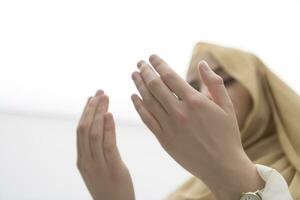 portrait of beautiful muslim woman in fashionable dress with hijab making traditional prayer to God keeps hands in praying gesture isolated on white background photo