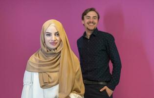 Portrait of happy young muslim couple standing isolated on pink background photo