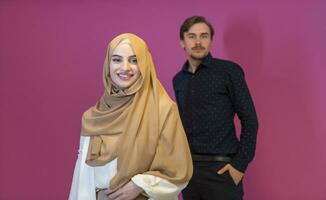 Portrait of happy young muslim couple standing isolated on pink background photo