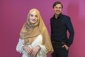 Portrait of happy young muslim couple standing isolated on pink background photo