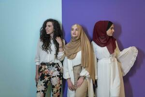 grupo retrato de hermosa musulmán mujer dos de ellos en un de moda vestir con hijab aislado en un vistoso antecedentes foto