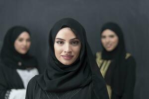 Group portrait of beautiful Muslim women in a fashionable dress with hijab isolated on black background photo