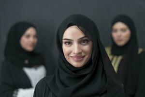 Group portrait of beautiful Muslim women in a fashionable dress with hijab isolated on black background photo