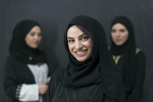 Group portrait of beautiful Muslim women in a fashionable dress with hijab isolated on black background photo