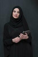 Young modern muslim business woman using smartphone wearing hijab clothes in front of black chalkboard photo