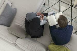 Top view photo of traditional muslim family parents with children reading Quran and praying together