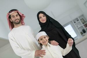 Portrait of a young happy Arabian Muslim family couple with a son in traditional clothes spending time together photo