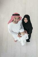 Portrait of a young happy Arabian Muslim family couple with a son in traditional clothes spending time together photo