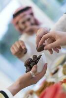 moderno multiétnico musulmán familia compartiendo un cuenco de fechas mientras disfrutando iftar cena juntos durante un Ramadán banquete a hogar foto
