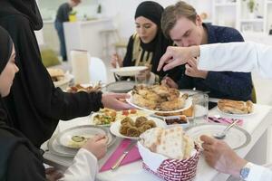 eid Mubarak musulmán familia teniendo iftar cena Bebiendo agua a descanso banquete. comiendo tradicional comida durante Ramadán banquete mes a hogar. el islámico halal comiendo y Bebiendo a moderno occidental isla foto