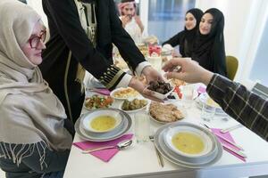 moderno multiétnico musulmán familia compartiendo un cuenco de fechas mientras disfrutando iftar cena juntos durante un Ramadán banquete a hogar foto