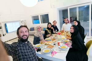 eid Mubarak musulmán familia teniendo iftar cena tomando imágenes con móvil teléfono mientras comiendo tradicional comida durante Ramadán banquete mes a hogar. el islámico halal comiendo y Bebiendo islámico famil foto