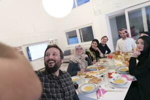 eid Mubarak musulmán familia teniendo iftar cena tomando imágenes con móvil teléfono mientras comiendo tradicional comida durante Ramadán banquete mes a hogar. el islámico halal comiendo y Bebiendo islámico famil foto