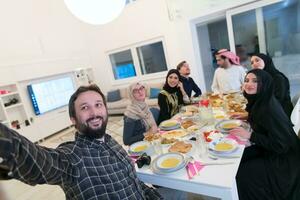 eid Mubarak musulmán familia teniendo iftar cena tomando imágenes con móvil teléfono mientras comiendo tradicional comida durante Ramadán banquete mes a hogar. el islámico halal comiendo y Bebiendo islámico famil foto