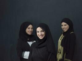 grupo retrato de hermosa musulmán mujer en un de moda vestir con hijab aislado en negro antecedentes foto