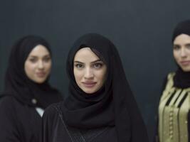 Group portrait of beautiful Muslim women in a fashionable dress with hijab isolated on black background photo